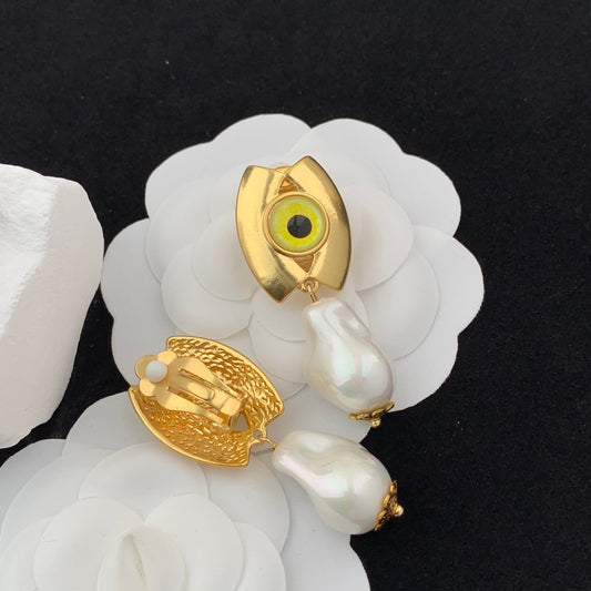 Gold and pearl earrings on a white shell against a black background