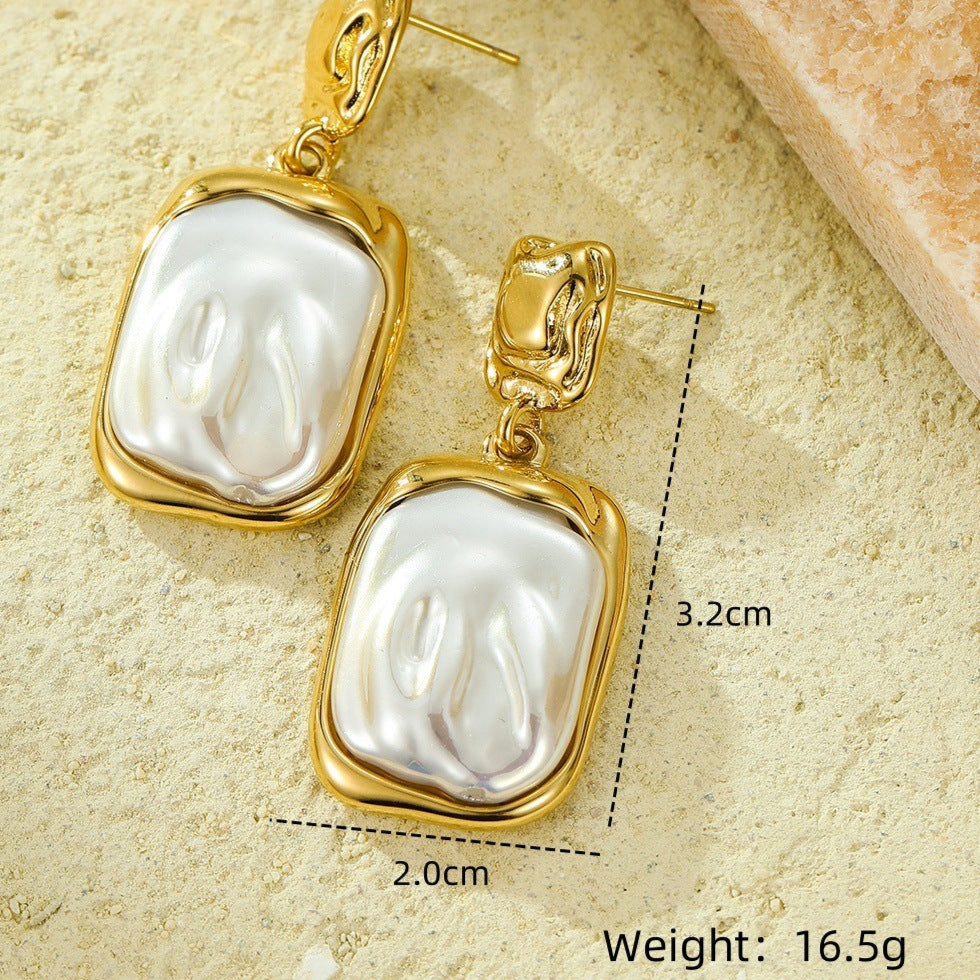 Gold earrings with pearls on a textured beige surface, showing measurements and weight.