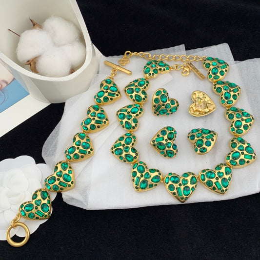 Gold and green jewelry set on a white cloth with a black background