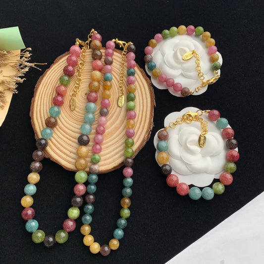 Colorful beaded necklace on a wooden stand with matching earrings on a black background