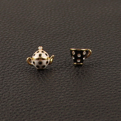 Teapot and teacup-shaped earrings on a dark textured surface