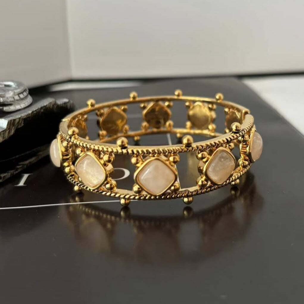 Gold bracelet with stone accents on a reflective surface