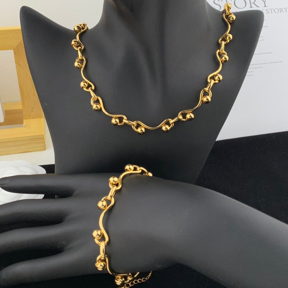 Gold necklace and bracelet set on a black mannequin
