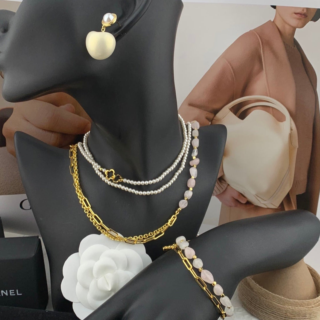 Black mannequin display with pearl jewelry and Chanel box in the background