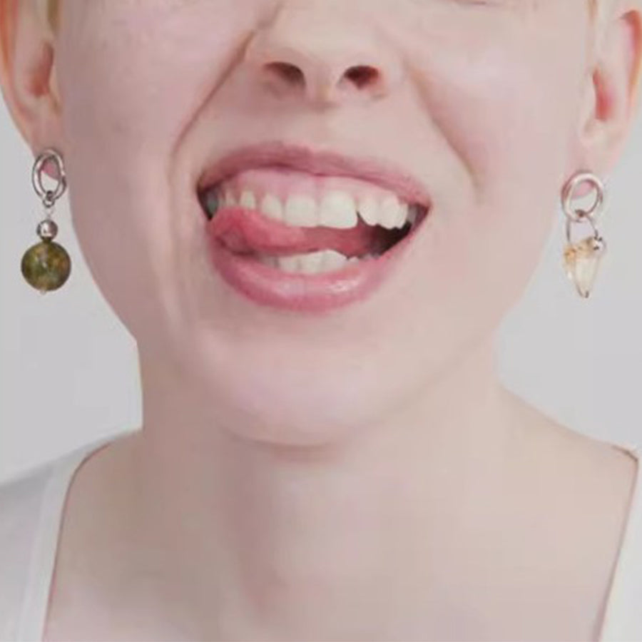 Close-up of a person wearing earrings with a neutral background