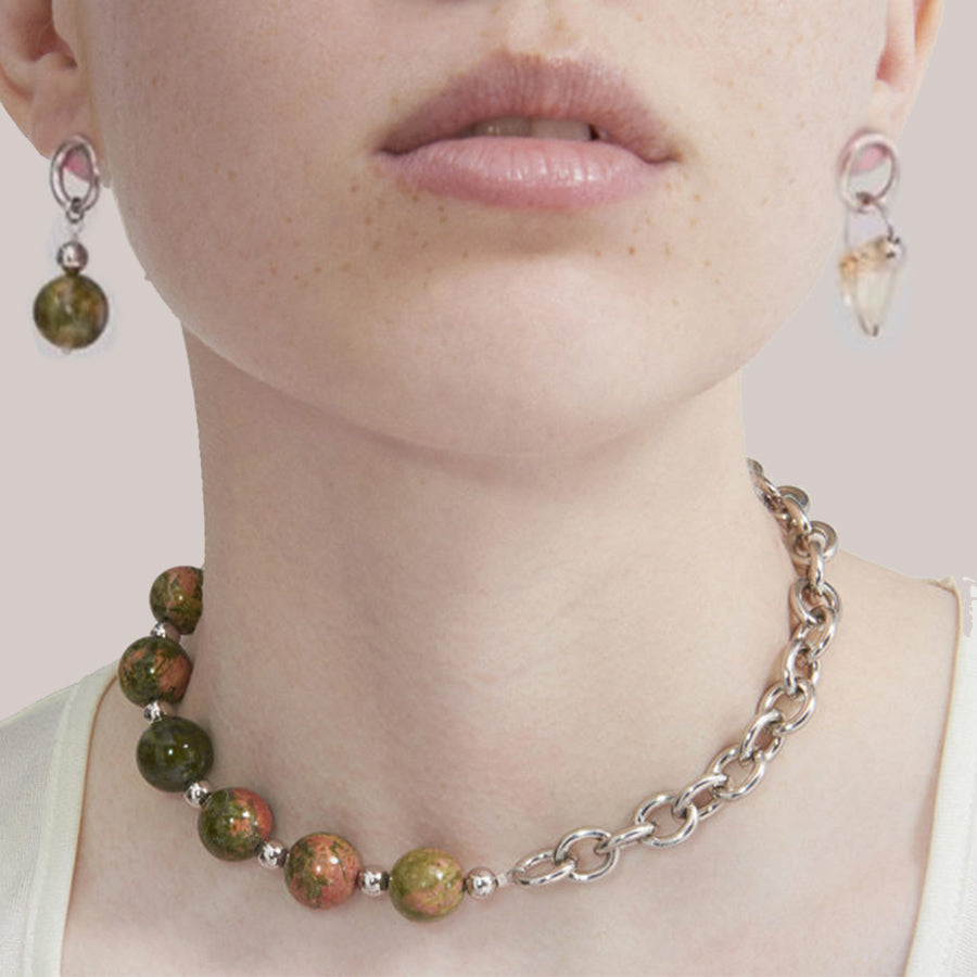 Necklace with green beads and silver chain worn by a person, with earrings visible.