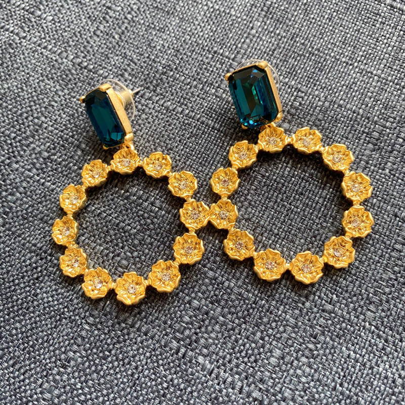 Gold hoop earrings with blue gemstones on a gray background