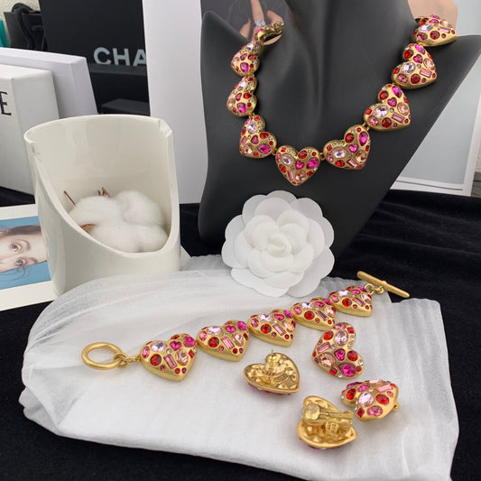 Gold jewelry set with heart-shaped designs on a white cloth, with a black background.