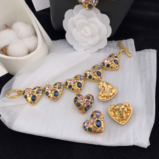 Gold bracelet with heart-shaped charms on a white cloth with a white flower in the background