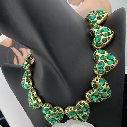Gold necklace with green gemstones on a mannequin bust.