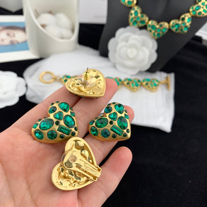 Gold and green jewelry set held in a hand with blurred background