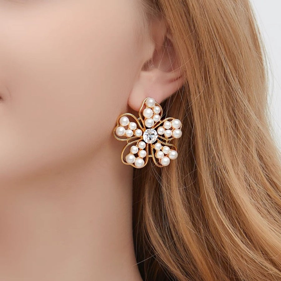 Close-up of a woman wearing a floral pearl earring with a clear gemstone.
