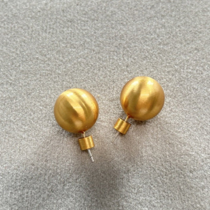 Pair of gold spherical earrings on a gray background