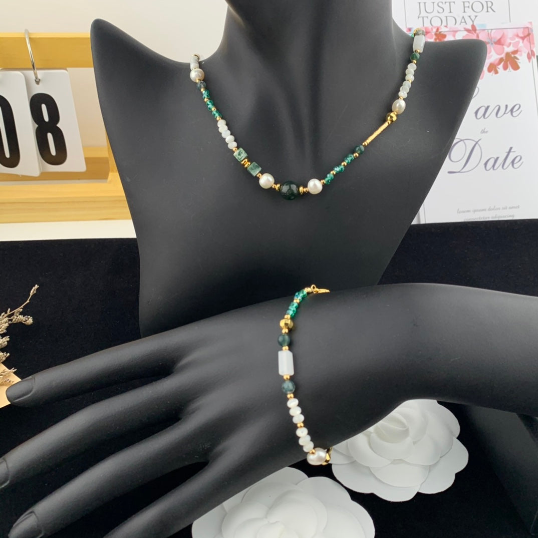 Beaded necklace and bracelet on a mannequin hand with a blurred background
