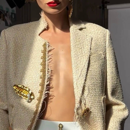 Beige blazer with gold buttons and trim on a neutral background