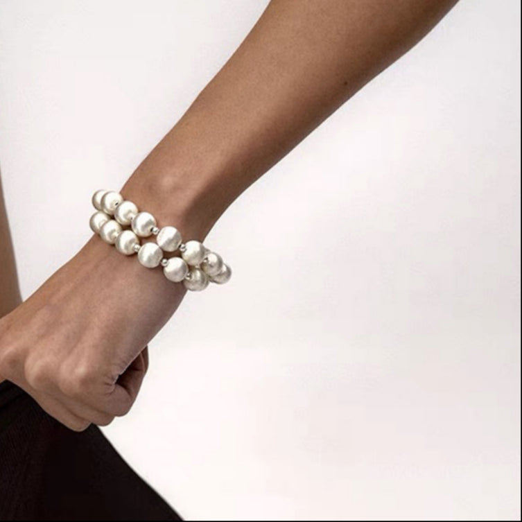 Pearl bracelet on a person's wrist against a neutral background