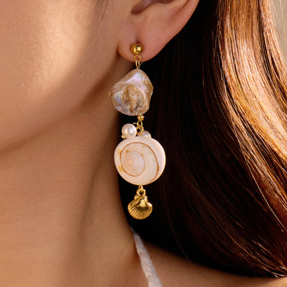 Close-up of a woman wearing elegant earrings with pearls and gold accents.