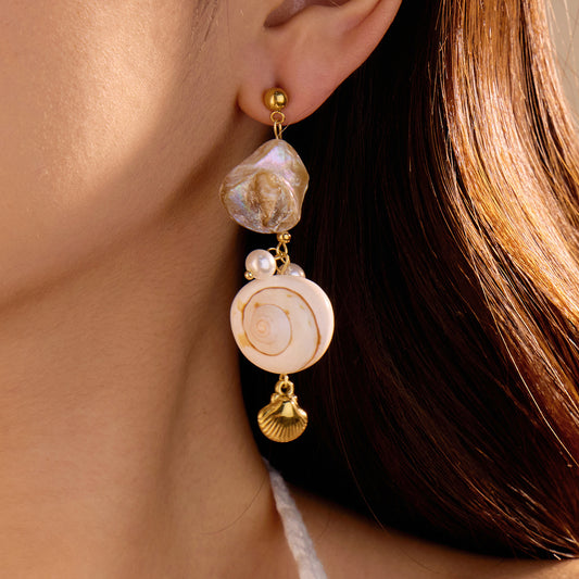 Close-up of a woman wearing elegant earrings with pearls and gold accents.