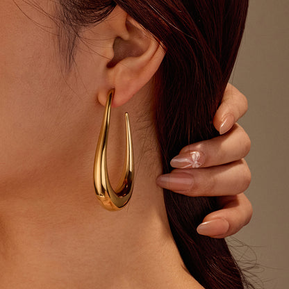 Gold hoop earring worn by a person with a neutral background
