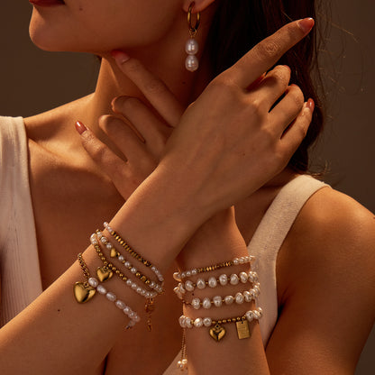 Close-up of a person wearing multiple bracelets and an earring with a warm, brownish hue.