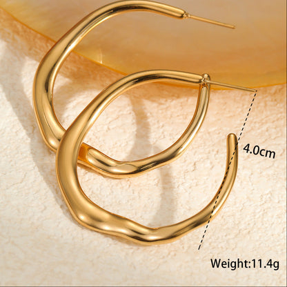 Gold hoop earrings on a textured beige surface with measurement details.