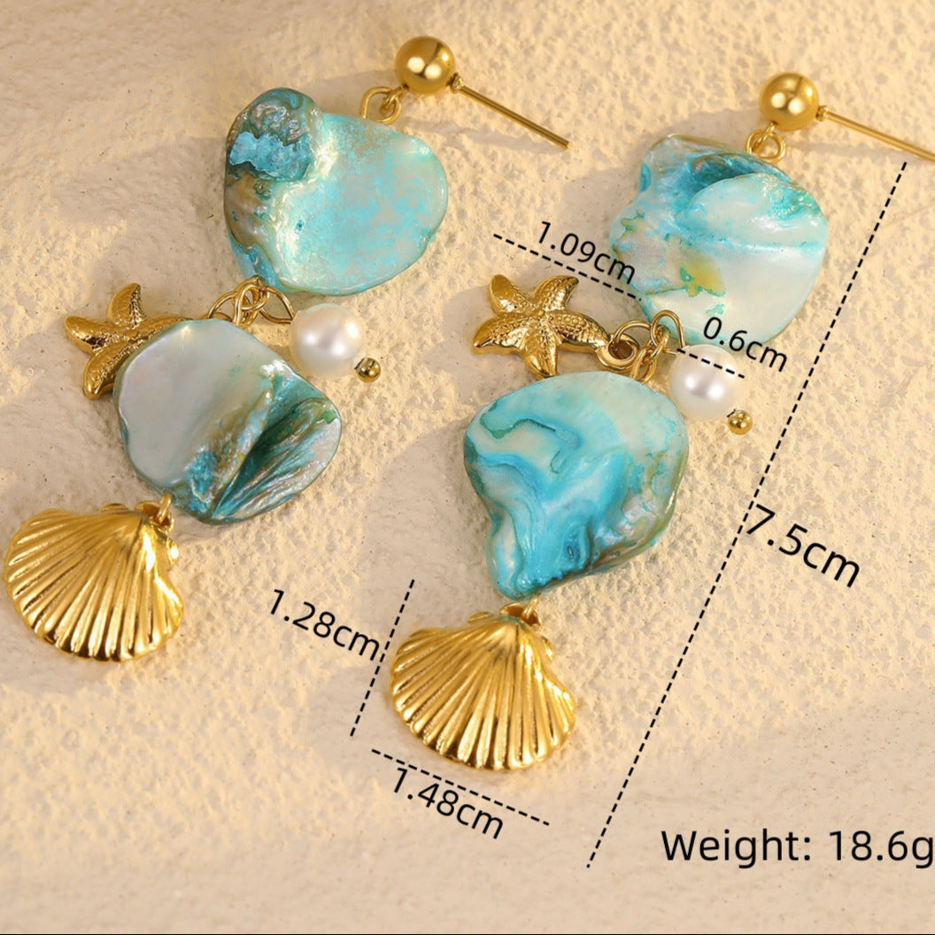 Pair of earrings with turquoise stones and gold accents on a textured beige background