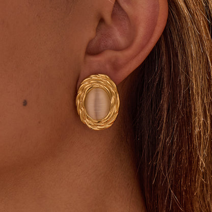 Gold earring worn on an ear with a close-up view