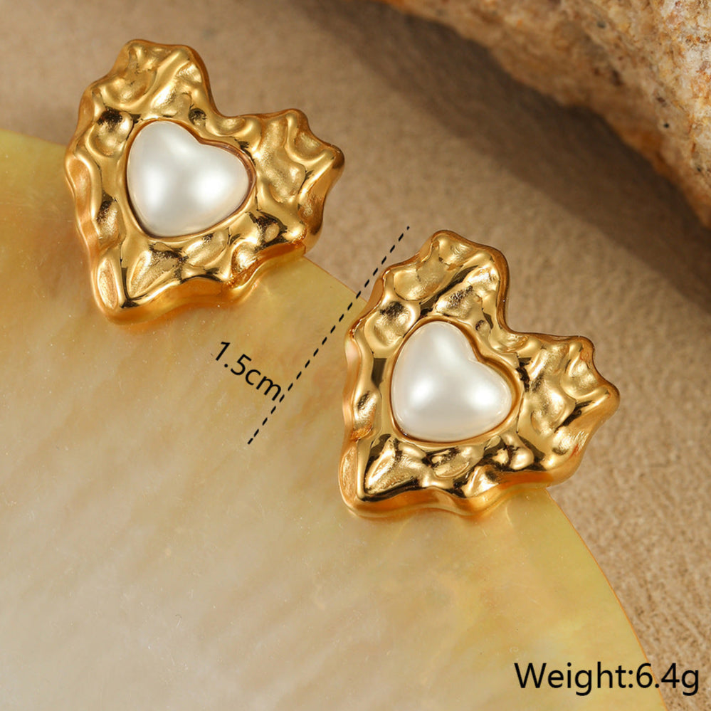 Gold heart-shaped earrings with a pearl center on a beige surface, showing measurement and weight details.