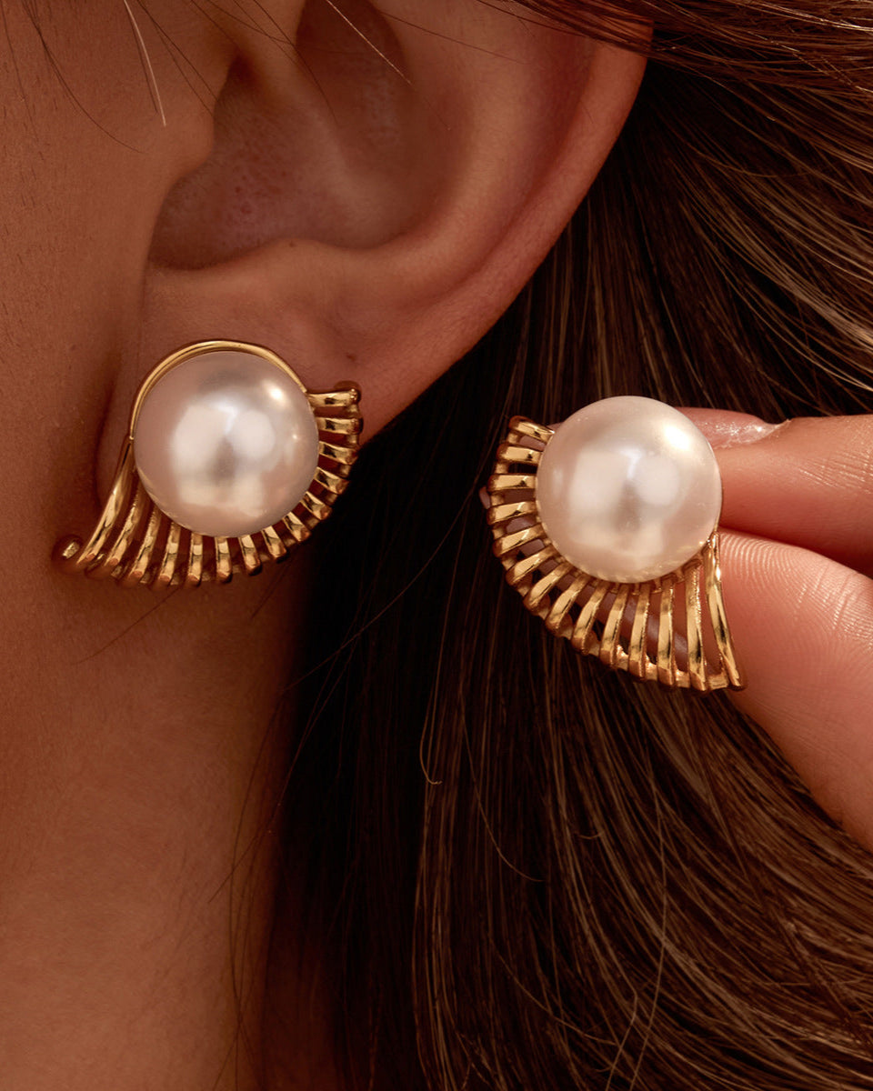 Pearl earrings with gold fixtures worn by a person