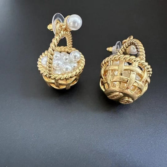 Gold earrings with pearl-like beads on a dark background