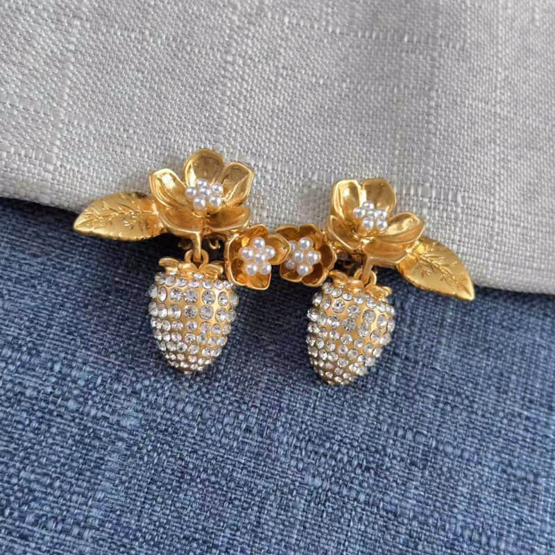 Gold and pearl earrings on a textured fabric background