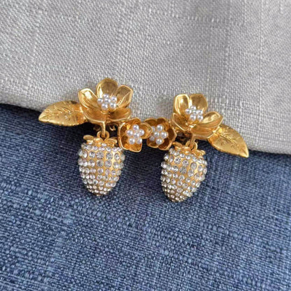 Gold and pearl earrings on a textured fabric background