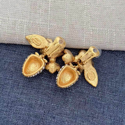 Gold bracelet with heart-shaped charms on a textured fabric background