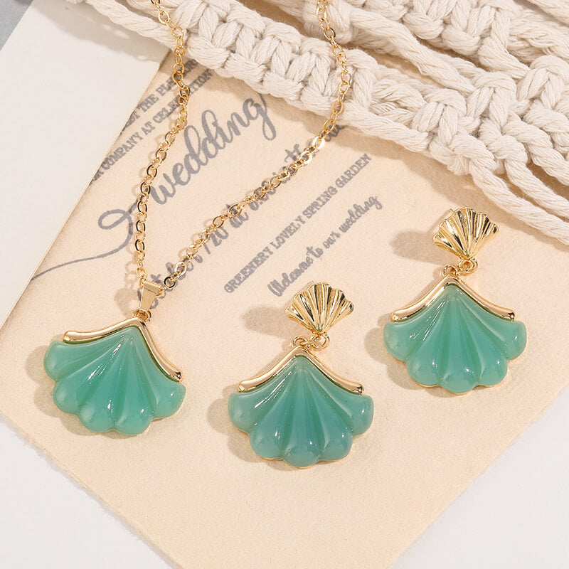 Turquoise shell-shaped earrings with gold accents on a wedding card background