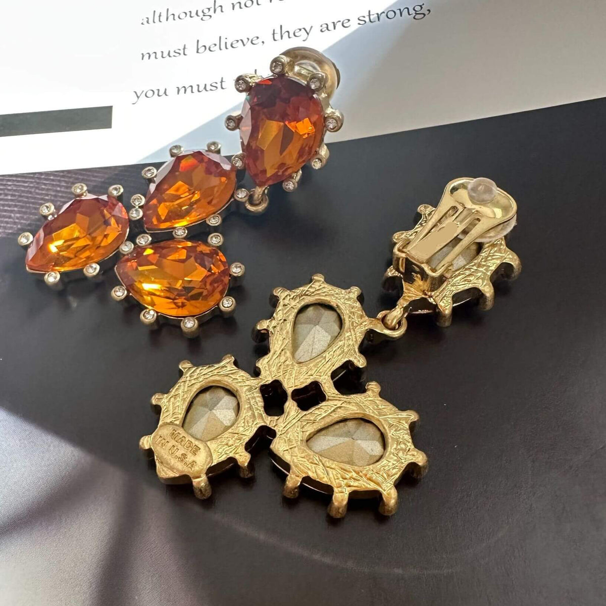 Gold earrings with orange gemstones on a dark surface