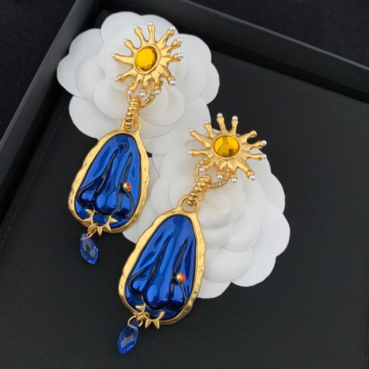 Elegant earrings with blue drops and gold accents on a black background