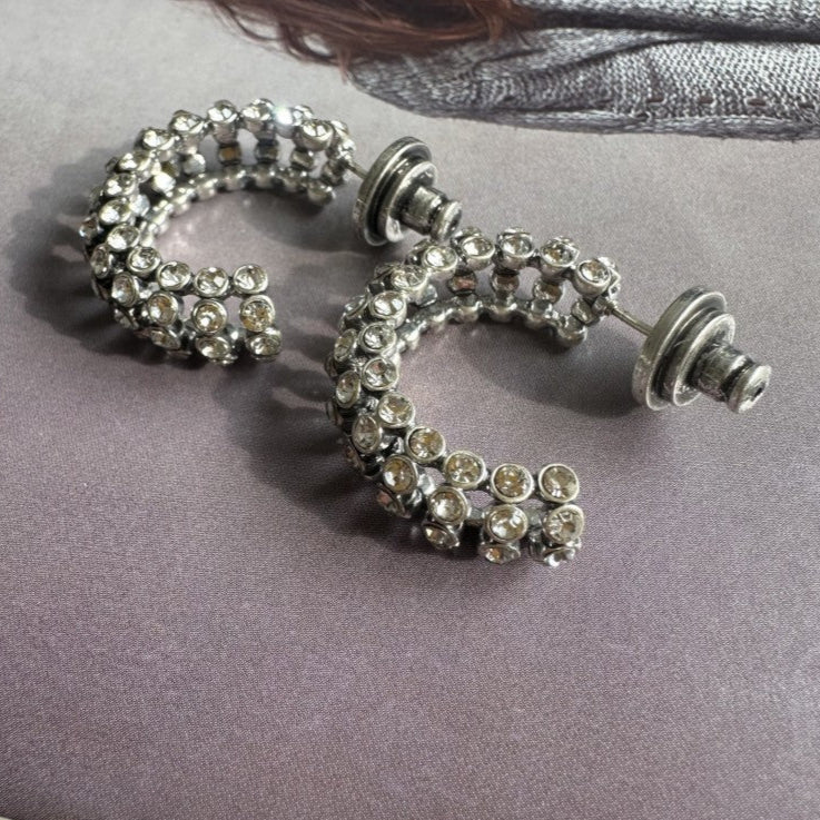 Silver hoop earrings with gemstones on a gray surface