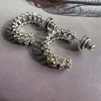 Silver hoop earrings with gemstones on a gray surface