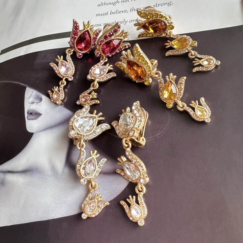 Gold earrings with colorful gemstones on a magazine background