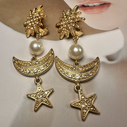 Gold earrings with stars, moons, and pearls on a neutral background
