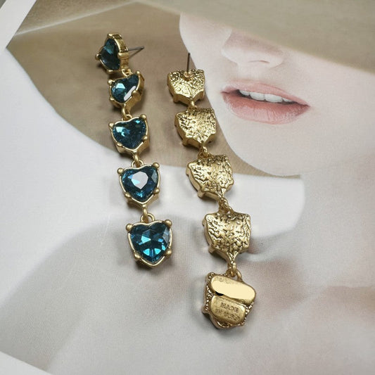 Gold earrings with blue gemstones on a white background