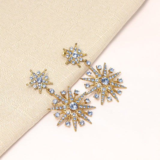 Gold and crystal earrings on a beige fabric background