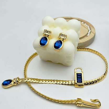 Gold bracelet with blue gemstones and matching earrings on a white background