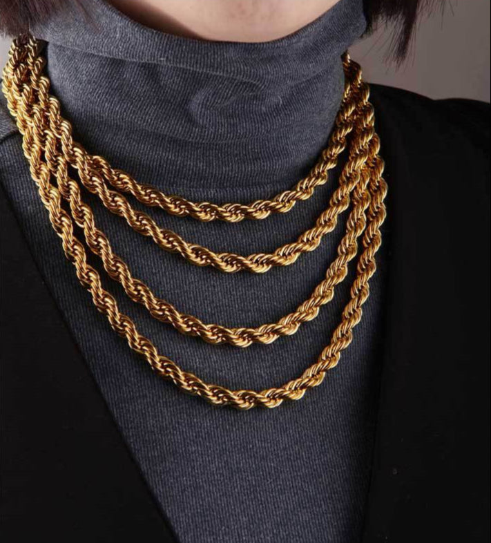 Gold chain necklace worn by a person on a plain background
