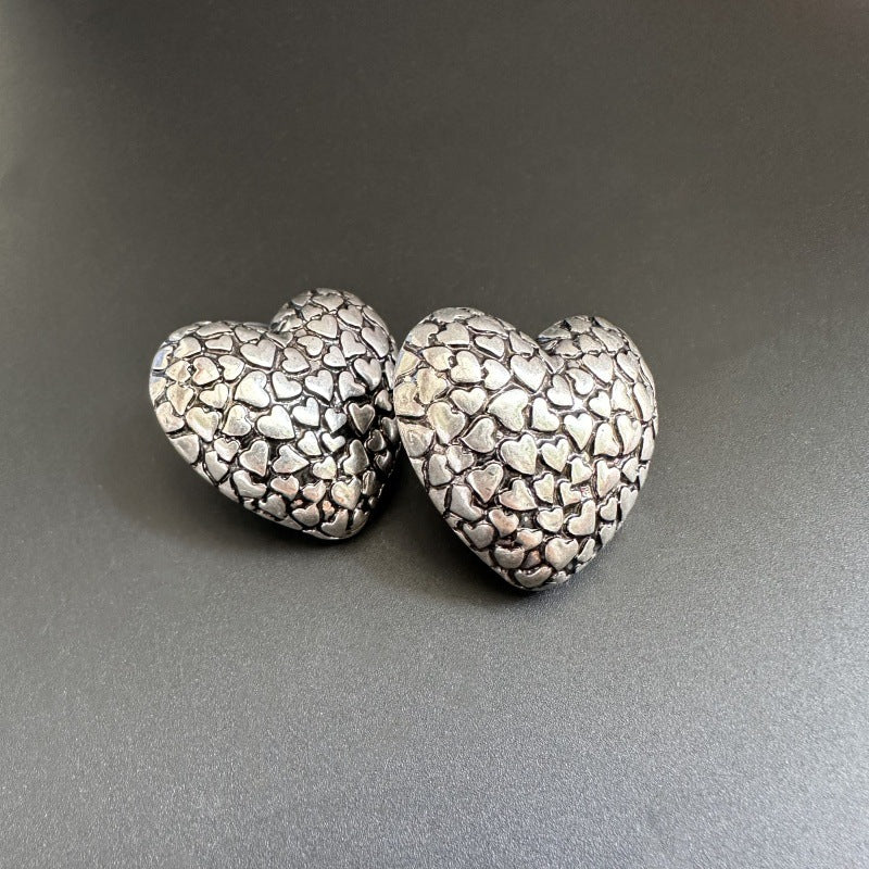 Pair of silver heart-shaped earrings on a gray background