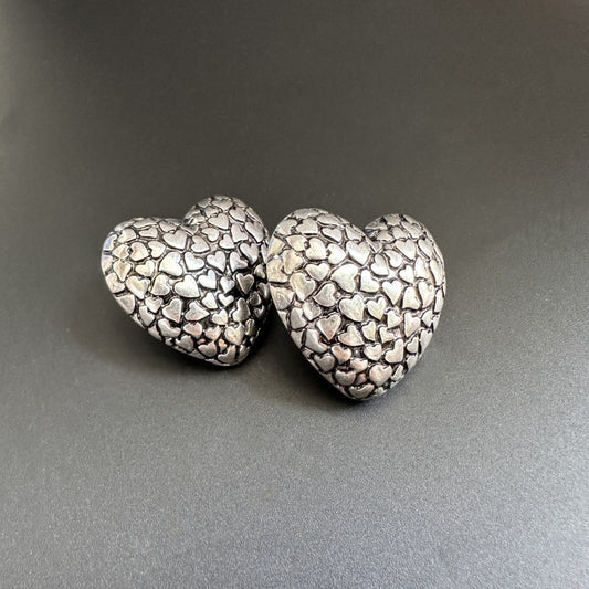 Pair of silver heart-shaped earrings on a gray background