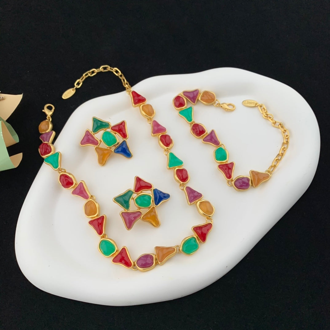 Colorful geometric necklace and bracelet set on a white stone surface with a black background