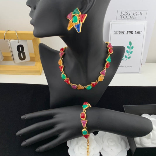 Colorful jewelry set on a black mannequin hand with a calendar and decorative items in the background.