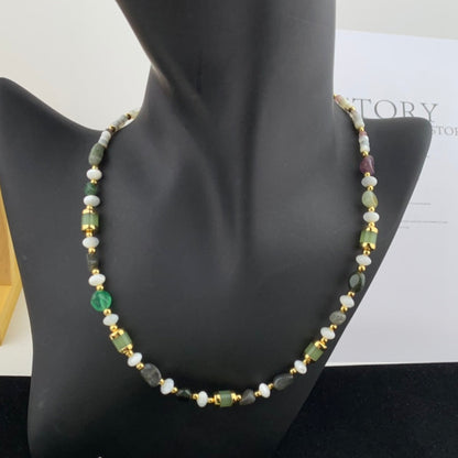Necklace with green and gold beads on a mannequin bust with a white background