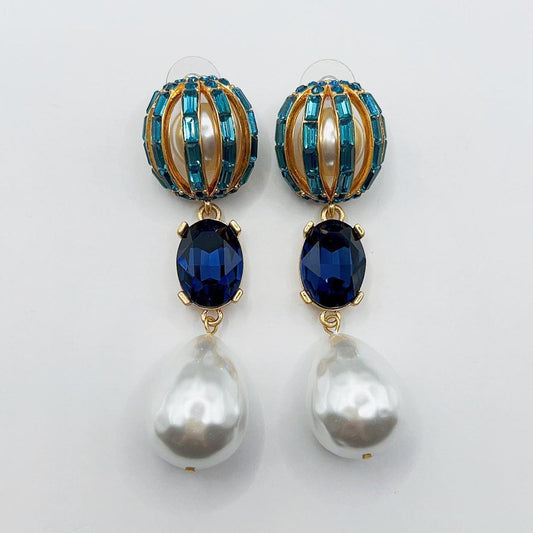 Pair of earrings with blue gemstones and pearl drops on a white background